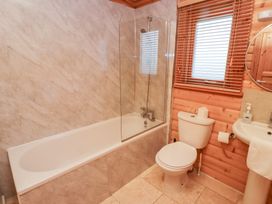 A bathroom with a bathtub, shower, toilet and sink at Heather Cottages - Grey Heron in Bamburgh