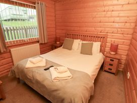 A bedroom with a bed and nightstand at Heather Cottages - Grey Heron in Bamburgh