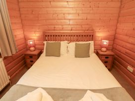 A bedroom with a bed and nightstands at Heather Cottages - Grey Heron in Bamburgh