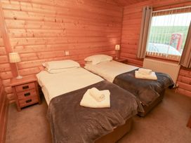 A bedroom with two beds and a nightstand at Heather Cottages - Grey Heron, Bamburgh