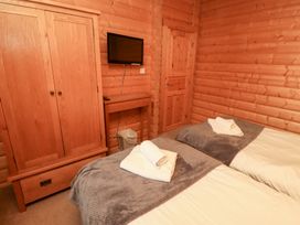 A bedroom with two beds and a wardrobe at Heather Cottages - Grey Heron in Bamburgh