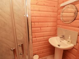 A bathroom with a shower, sink, and mirror at Heather Cottages - Grey Heron Bamburgh