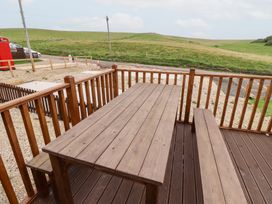 An outdoor area with a wooden table and benches at Heather Cottages - Grey Heron in Bamburgh