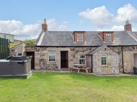An outdoor view of a cottage with a hot tub and table at Heather Cottages - Grey Seal Bamburgh