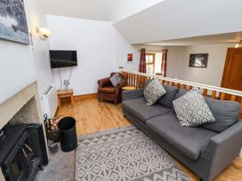 A living room with a sofa, armchair, and television at Heather Cottages - Grey Seal in Bamburgh
