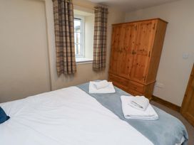 A bedroom with a bed and wardrobe at Heather Cottages - Grey Seal in Bamburgh