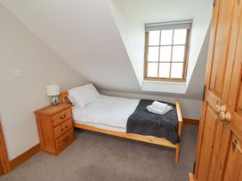 A bedroom with a single bed and nightstand at Heather Cottages - Grey Seal in Bamburgh
