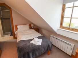 A bedroom with a bed and shower at Heather Cottages - Grey Seal Bamburgh