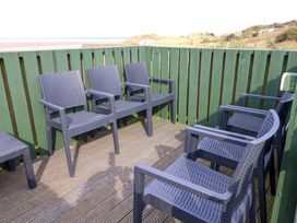An outdoor seating area with plastic chairs at Heather Cottages - Grey Seal in Bamburgh
