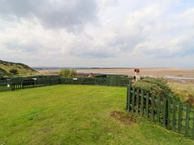 A garden with a fence and bench overlooking the sea at Heather Cottages - Grey Seal Bamburgh