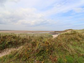 A beach view with sand and grass at Heather Cottages - Grey Seal in Bamburgh
