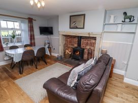 A living room with a sofa, dining table, and fireplace at Heather Cottages - Plover in Bamburgh