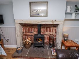 A living room with a fireplace and wood stove at Heather Cottages - Plover in Bamburgh