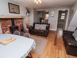 A living room with a fireplace, dining table, and sofa at Heather Cottages - Plover in Bamburgh