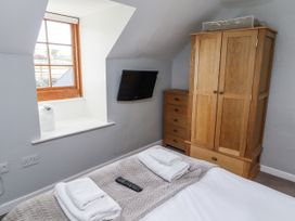 A bedroom with a bed and wardrobe at Heather Cottages - Plover in Bamburgh