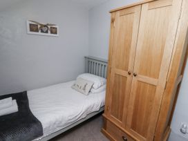 A bedroom with a bed and wardrobe at Heather Cottages - Plover in Bamburgh