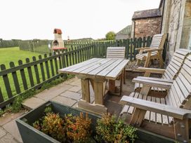 An outdoor area with wooden furniture and a fireplace at Heather Cottages - Plover in Bamburgh