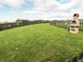 A garden with grass and a barbecue at Heather Cottages - Plover in Bamburgh