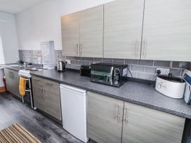 A kitchen with appliances and cabinets at Kittiwake Cottage, Budle Bay