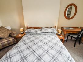 A bedroom with a bed, table, chairs, and lamp at Kittiwake Cottage, Budle Bay Bamburgh