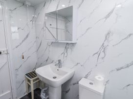 A bathroom with a sink, toilet and mirror at Kittiwake Cottage, Budle Bay