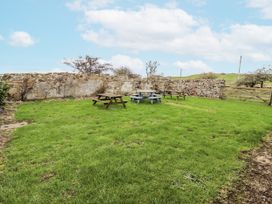 A garden area with picnic tables and a stone wall at Kittiwake Cottage, Budle Bay