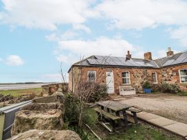An outdoor view of a house with solar panels and a garden at Kittiwake Cottage, Budle Bay