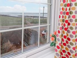 A window with a view of the sea and flowers at St Marys Cottages No4 Low Newton-by-the-Sea