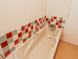 A bathroom with a bathtub and tiled wall at St Marys Cottages No4 Low Newton-by-the-Sea