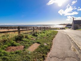 A landscape with a fence and road leading to the sea at St Marys Cottages No4 Low Newton-by-the-Sea