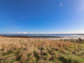A beach view with grass and water at St Marys Cottages No4 Low Newton-by-the-Sea