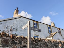 A house with a signpost indicating the England Coast Path at St Marys Cottages No4 Low Newton-by-the-Sea