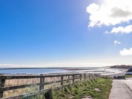 A beach with water, clouds, and a fence at St Marys Cottages No4 in Low Newton-by-the-Sea
