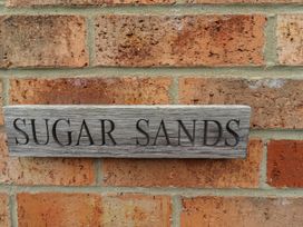 A sign reading SUGAR SANDS mounted on a brick wall at Sugar Sands in Longhoughton