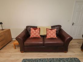 A living room with a brown sofa and cushions at Sugar Sands in Longhoughton