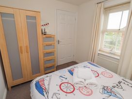 A bedroom with a wardrobe, chest of drawers, and a bed at Sugar Sands in Longhoughton