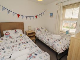 A bedroom with two beds and a nightstand at Sugar Sands in Longhoughton