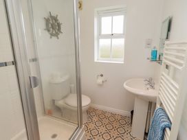 A bathroom with a shower, toilet, sink and window at Sugar Sands in Longhoughton