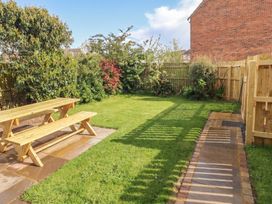 A garden with a wooden table and benches at Sugar Sands in Longhoughton