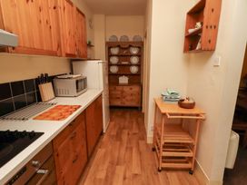 A kitchen with wooden cabinets and appliances at Wayside Cottage in Newton-by-the-Sea