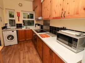A kitchen with a washing machine and a microwave at Wayside Cottage in Newton-by-the-Sea