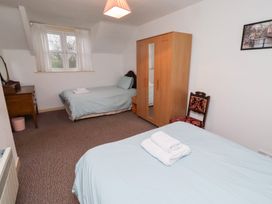 A bedroom with two beds and a wardrobe at Wayside Cottage in Newton-by-the-Sea