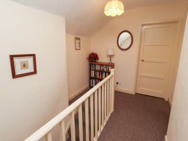 A hallway with a bookshelf and a lamp at Wayside Cottage in Newton-by-the-Sea