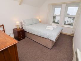 A bedroom with a bed, lamp, and desk at Wayside Cottage Newton-by-the-Sea