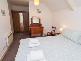A bedroom with a bed, dresser, and chair at Wayside Cottage in Newton-by-the-Sea