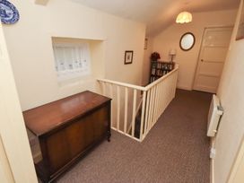 A hallway with a table and bookshelf at Wayside Cottage Newton-by-the-Sea