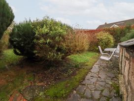 A garden with a stone pathway and table with chairs at Wayside Cottage in Newton-by-the-Sea