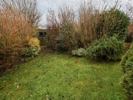 A garden with grass and shrubs at Wayside Cottage in Newton-by-the-Sea