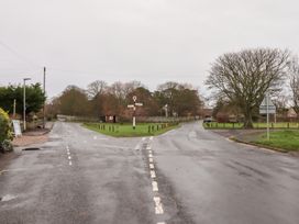 A road intersection with a signpost and trees at Wayside Cottage in Newton-by-the-Sea