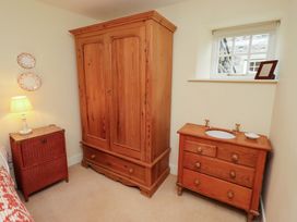 A bedroom with a wooden armoire and vanity at Wynding Down in Bamburgh